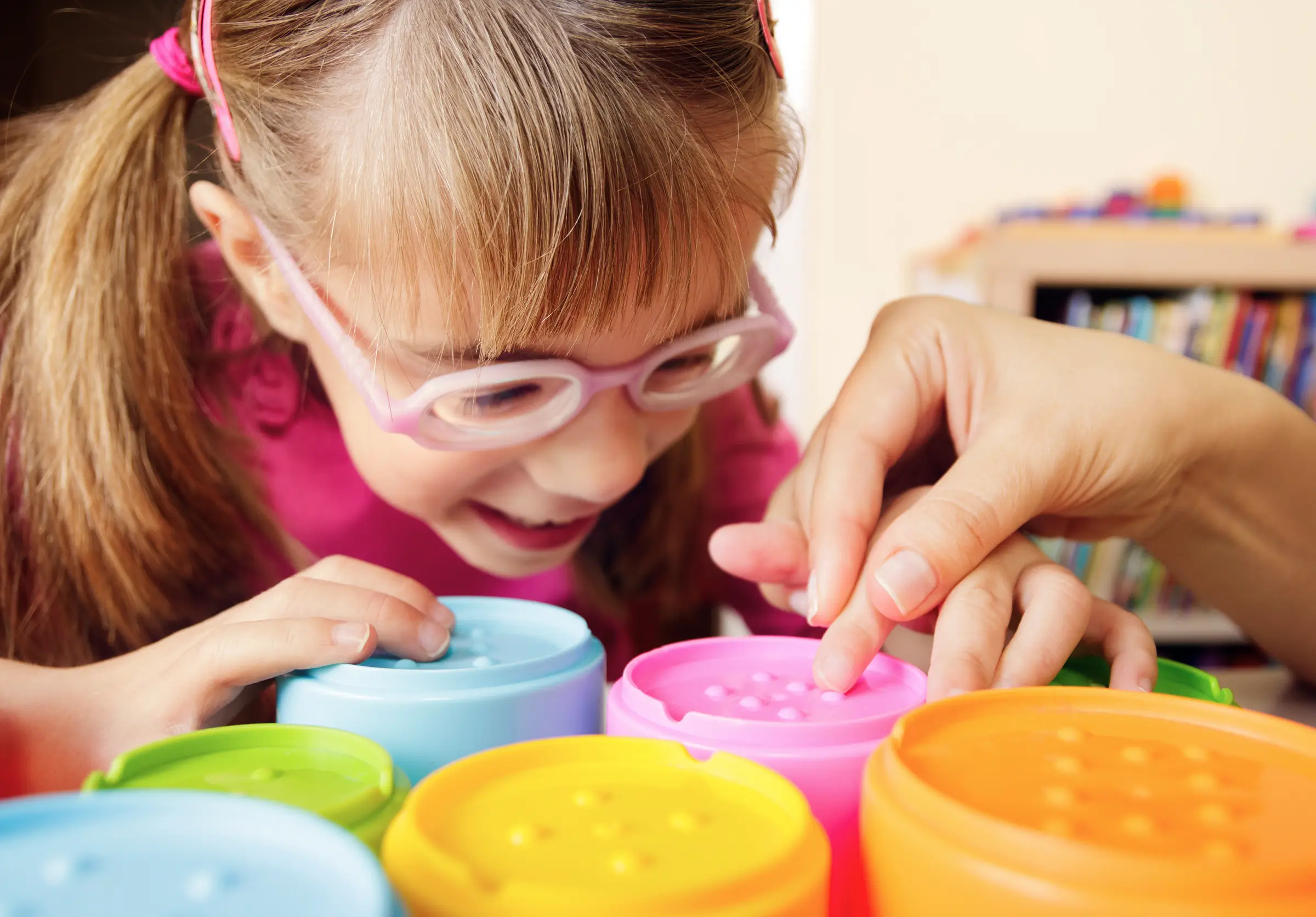 Girl in glasses playing with bright colored blocks.