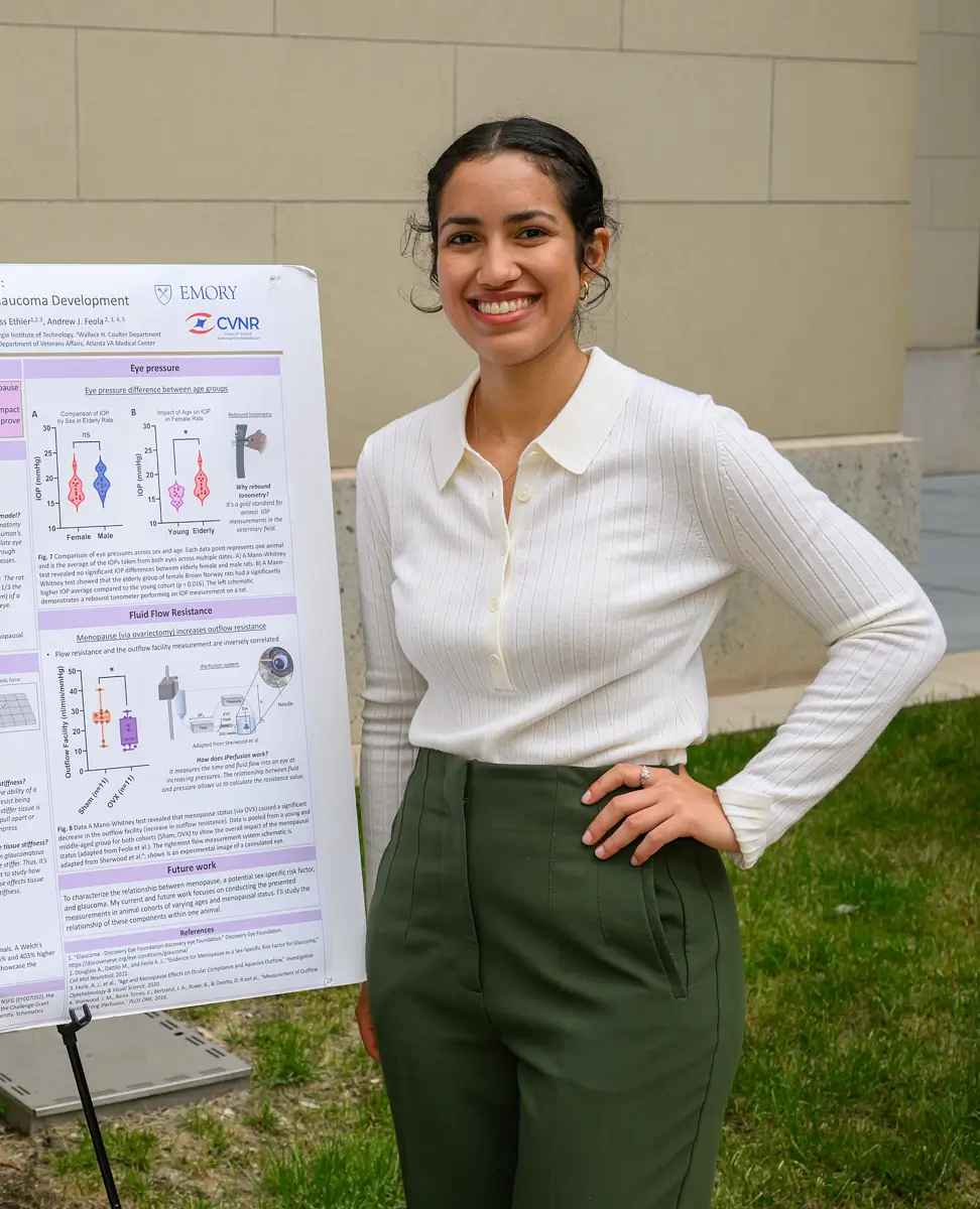 Woman standing in front of a presentation board to discuss the science behind new eye research.