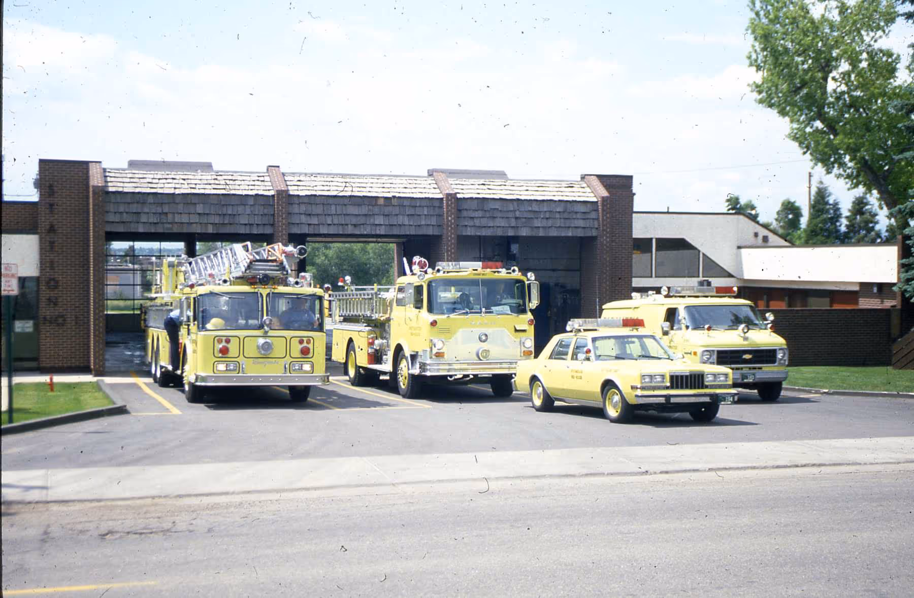 Historic photo of yellow Westminster Fire Department vehicles parked outside the fire station.