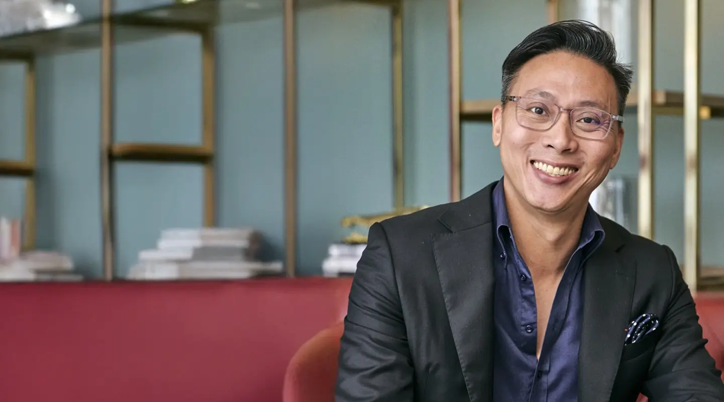 Portrait of Adrian Cher smiling in suit with testimonial overlay.