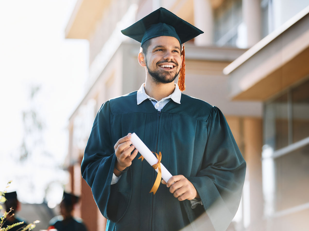 Happy young man smiles in graduation cap and gown