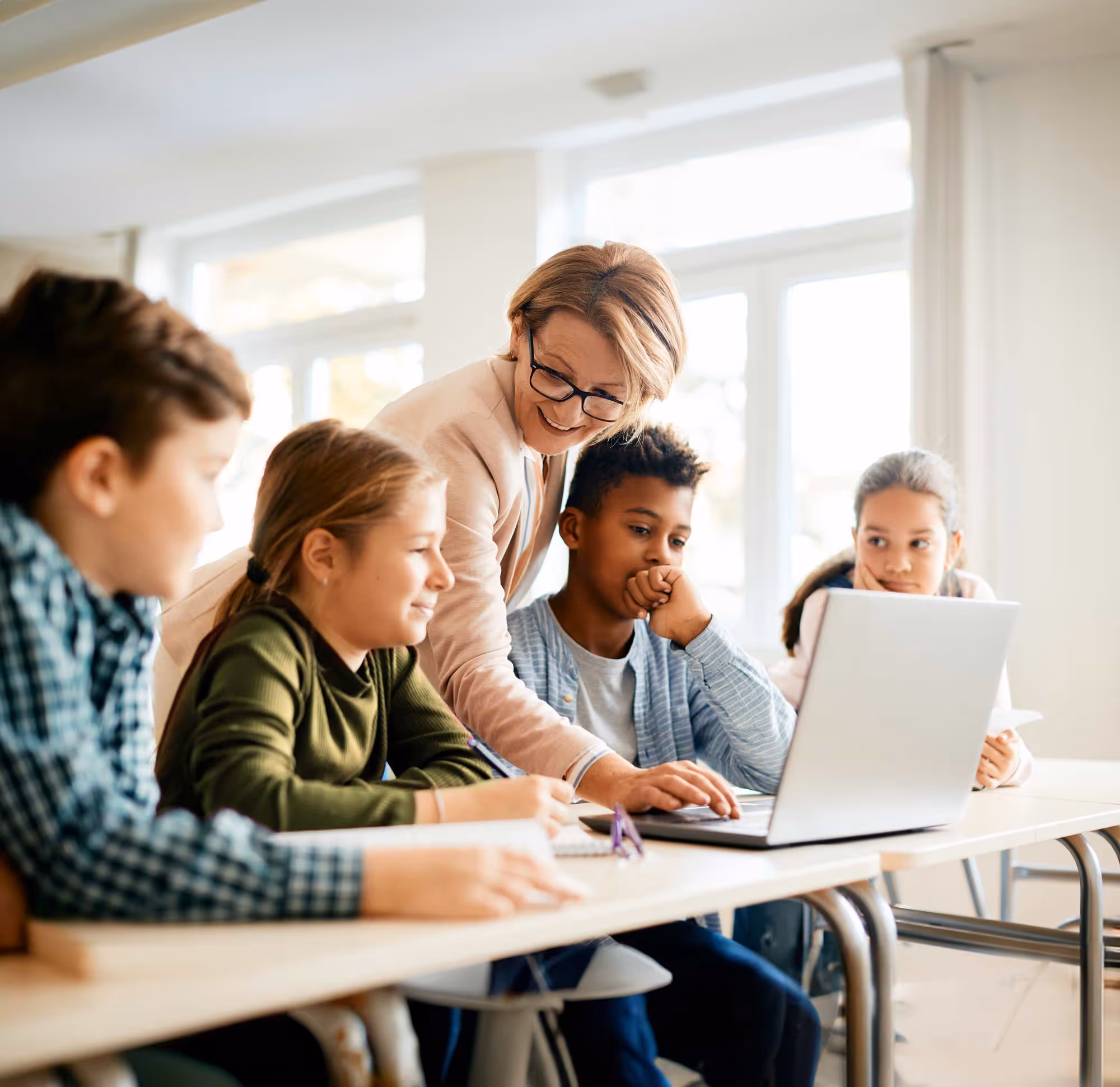 Teacher helping students with something on a laptop