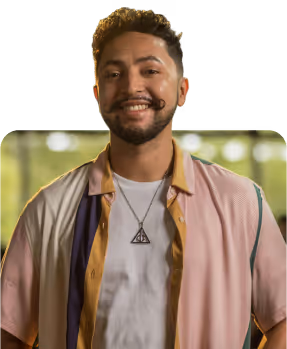 A handsome young man with a beard and curly hair smiles gently at the camera.
