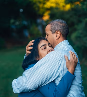 An older man and woman share a warm, comforting hug.