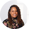 A professional, circular headshot of a smiling Black woman wearing a floral print top.