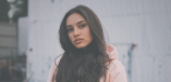 A portrait of a woman with long hair wearing a pink hoodie with the hood down.