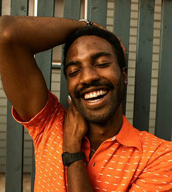 A man wearing an orange shirt and smiling.