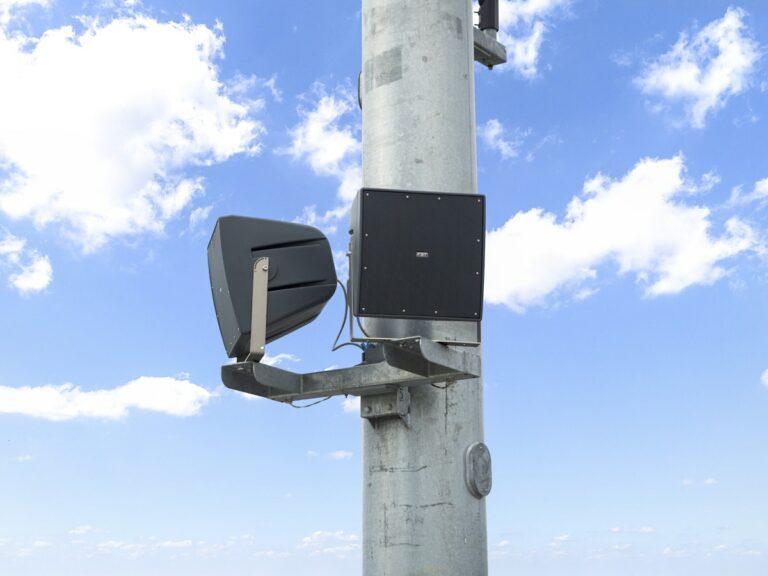 Speaker boxes fastened to a metal pole.