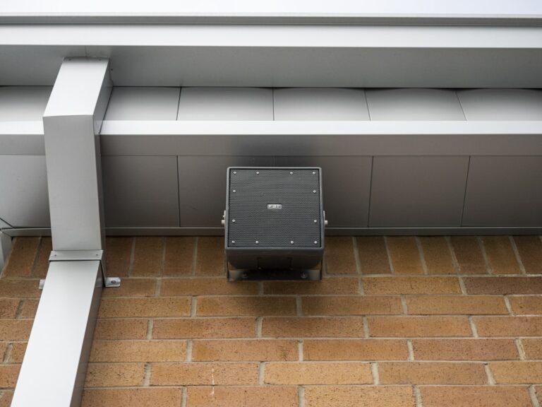 Speaker box hanging from a brick building.