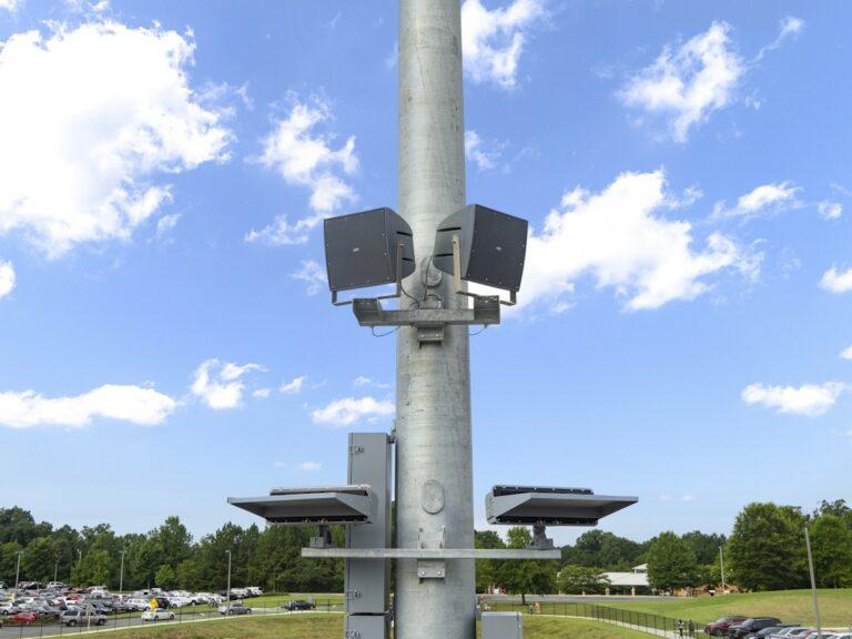 Speaker boxes fastened to a metal pole.