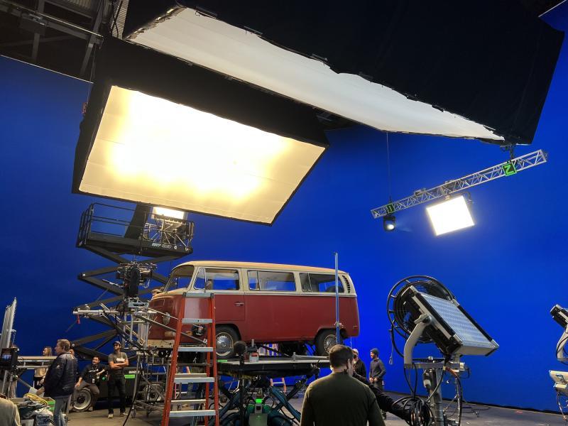 The Electric State Sci-Fi Adventure. A vintage VW bus on a lift on a film set.