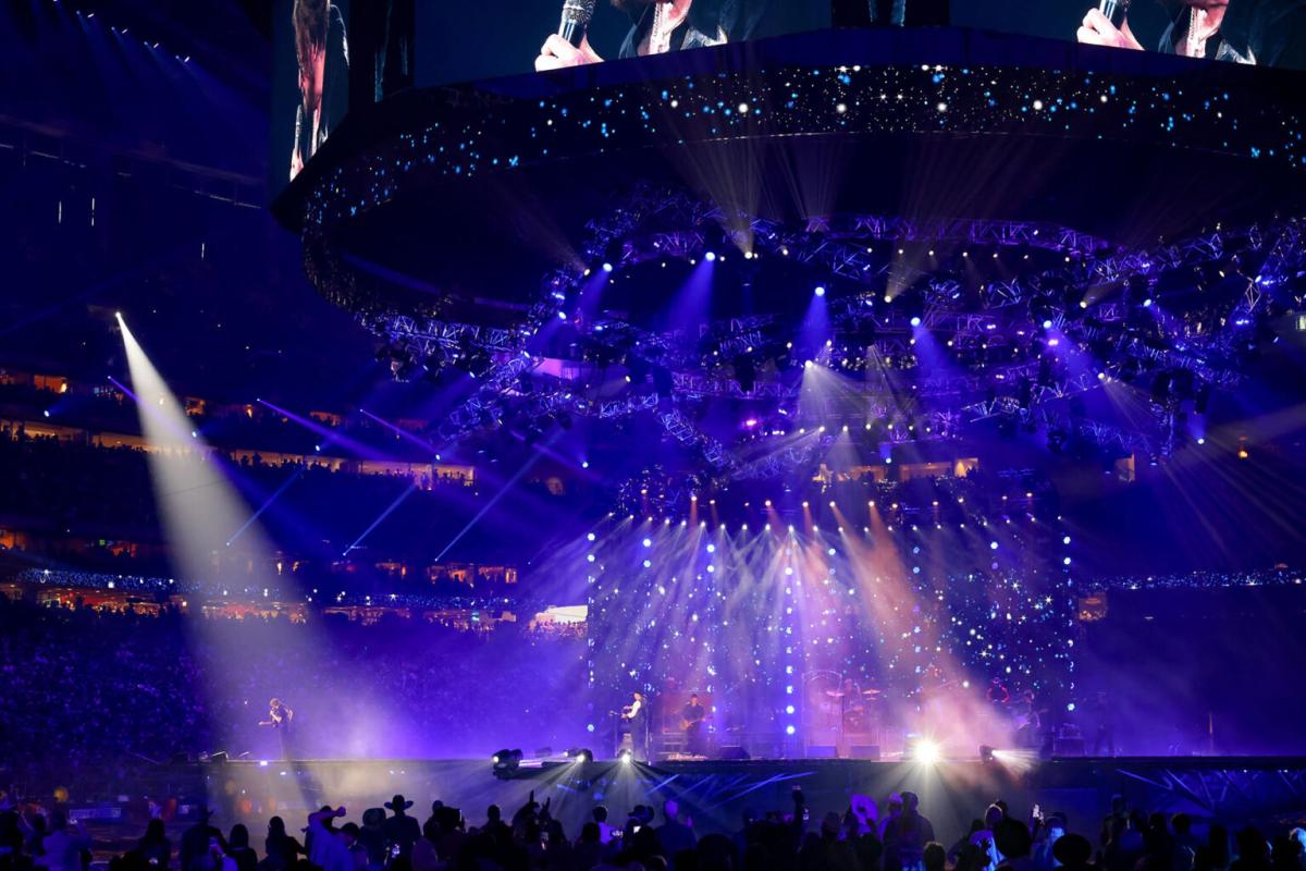 An audience watching a lit up stage featuring a couple people with instruments