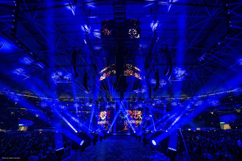Empty walkway onto circular stage illuminated by blue hued light.