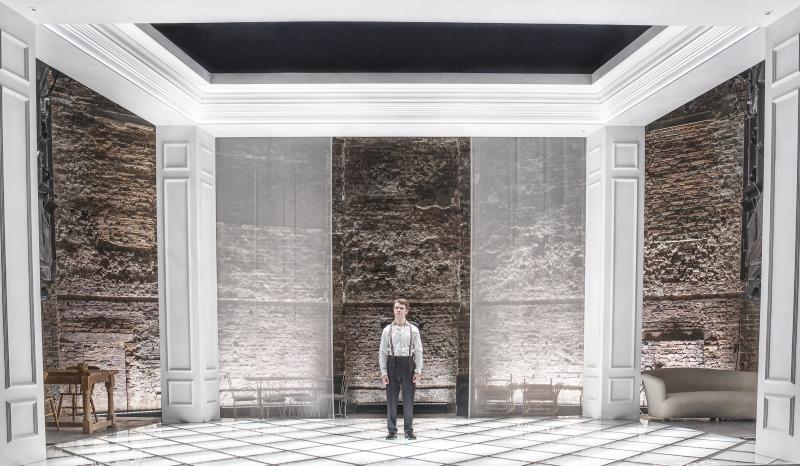 One man standing in the center of a brightly lit white room.