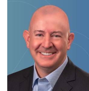 A bald white man in a blue shirt with a black blazer