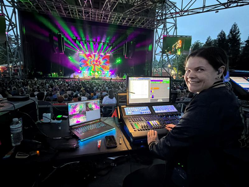Jamie Fadden sits at Hog desk with purple and green lighting on stage