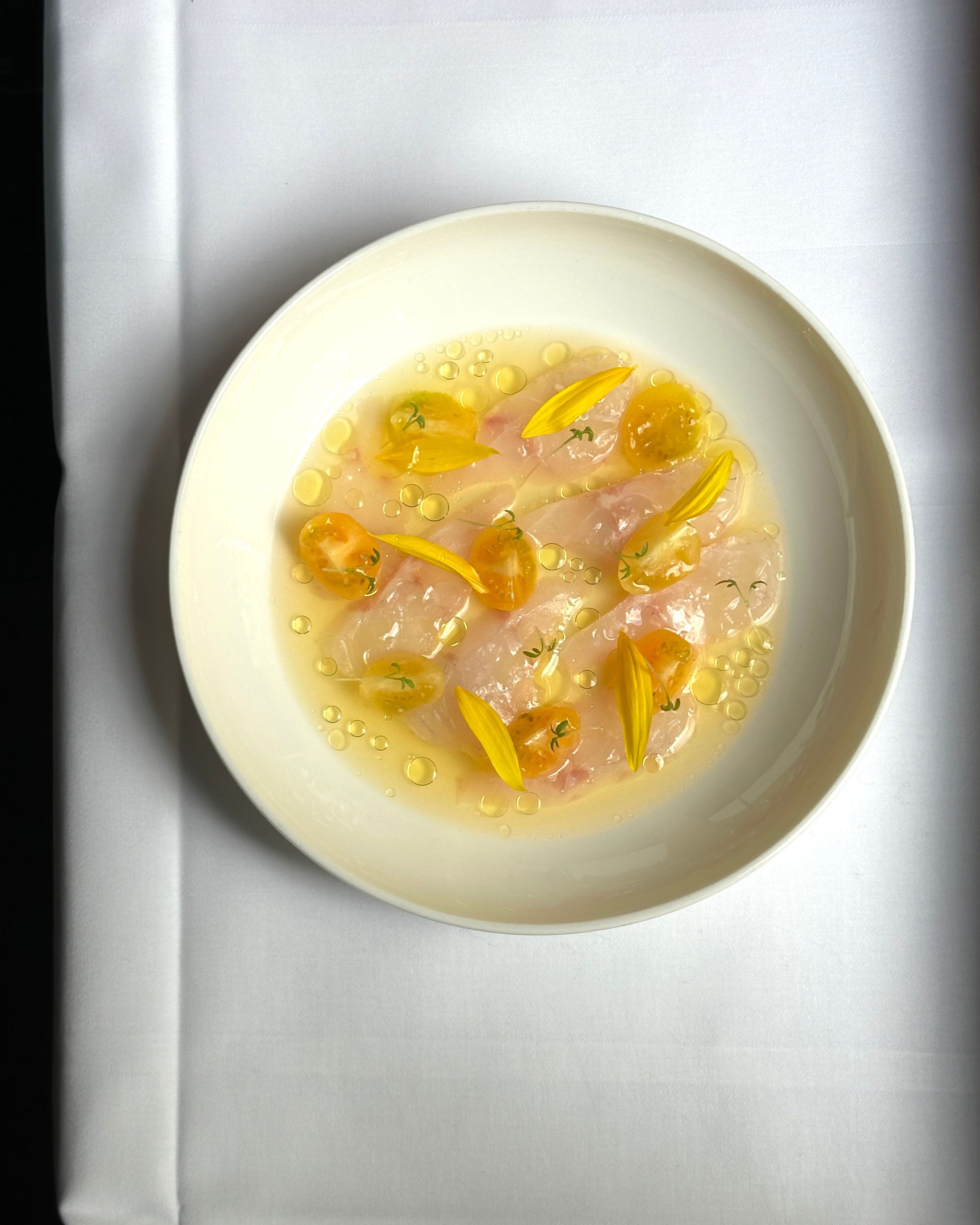 Teller mit Crudo Gericht auf weißer Tischdecke