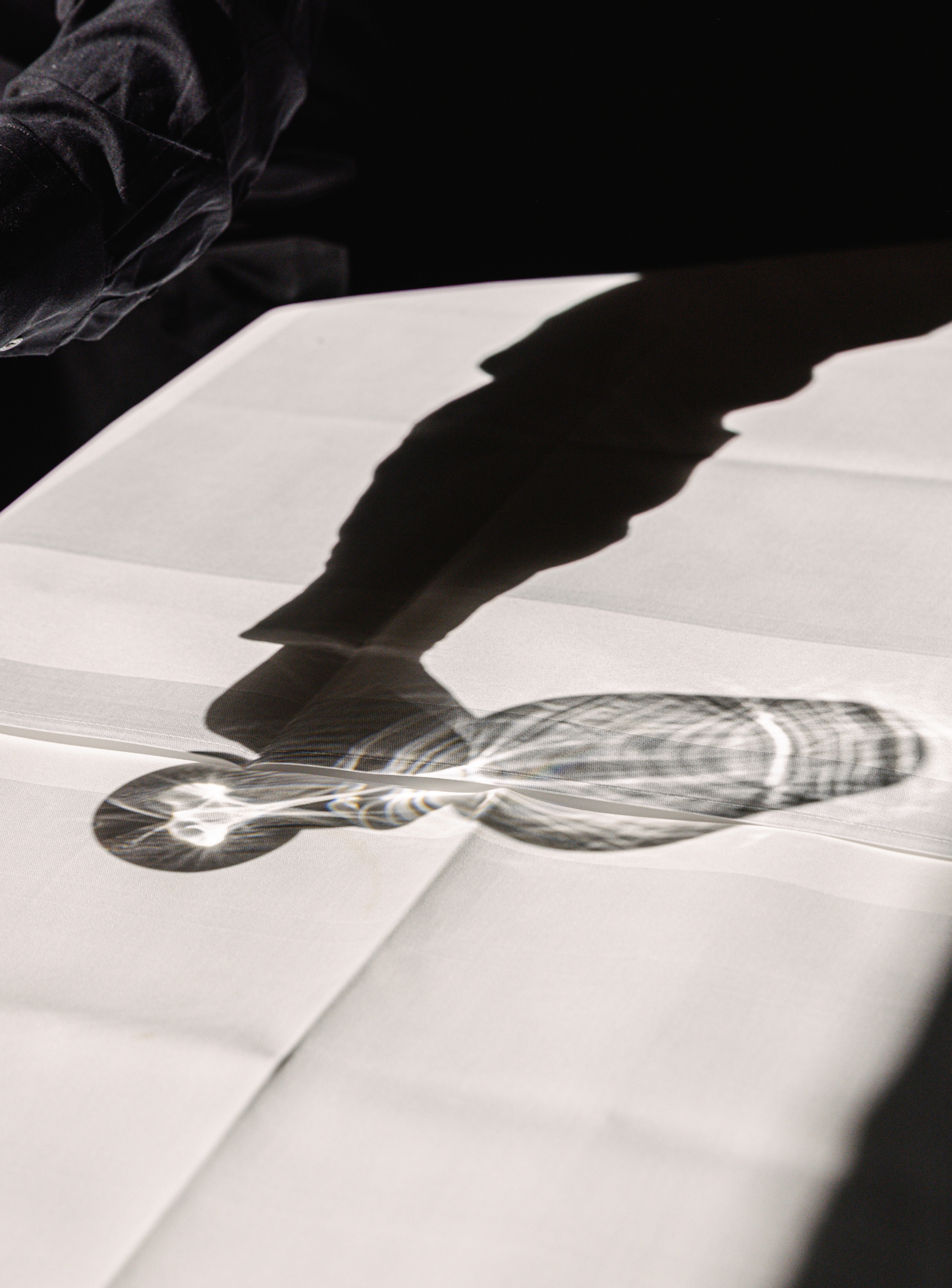 Schatten eines Weinglases auf einer weißen Tischdecke