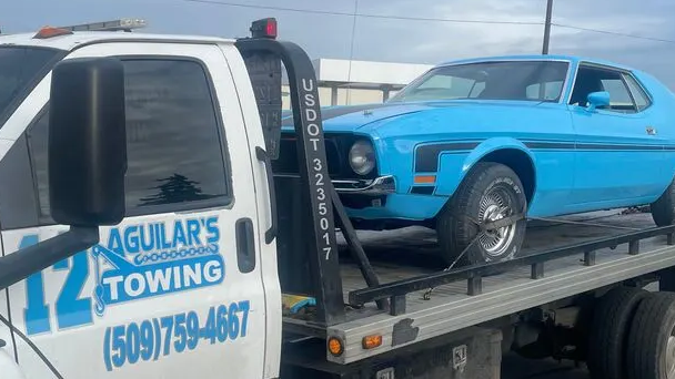 Aguilar's tow truck carrying a classic car with care