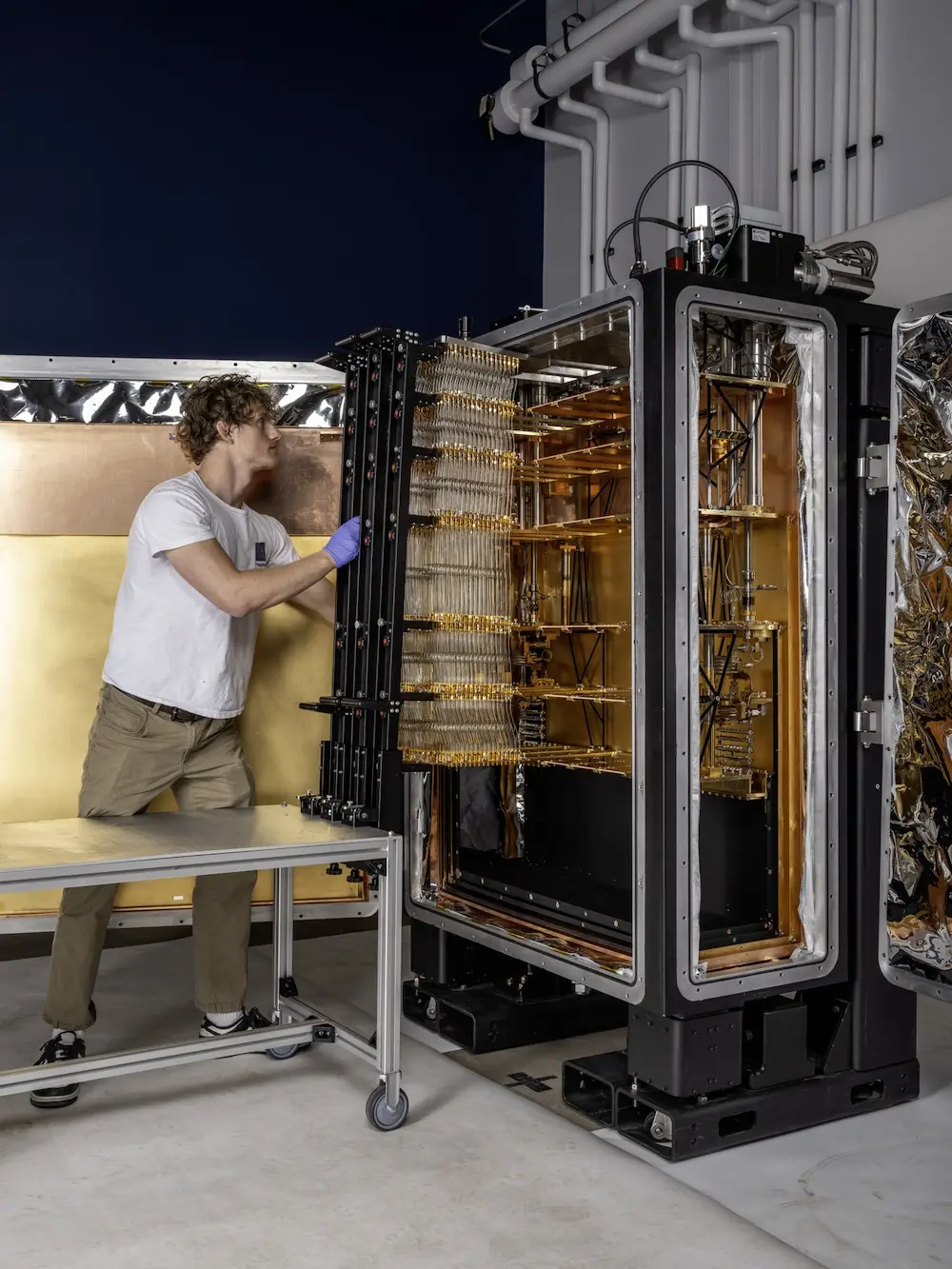 A Maybell employee swapping out wiring inside a dilution refrigerator