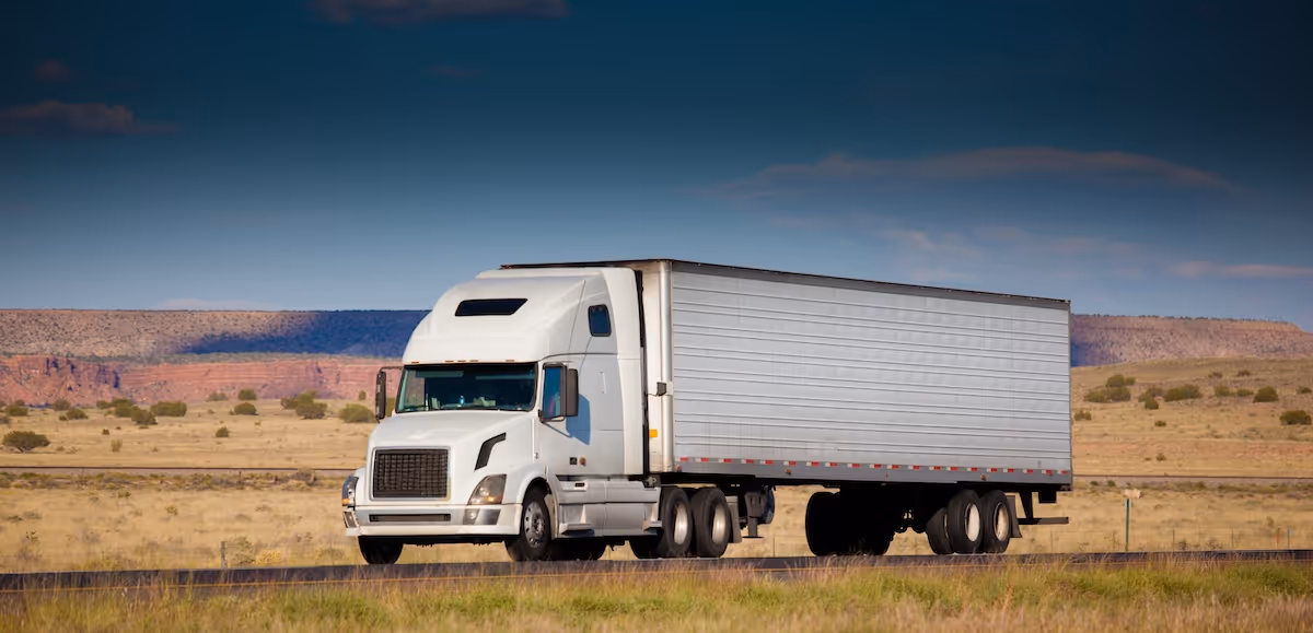 White semi-truck with a large trailer driving on a highway is best maintained with good lubricants