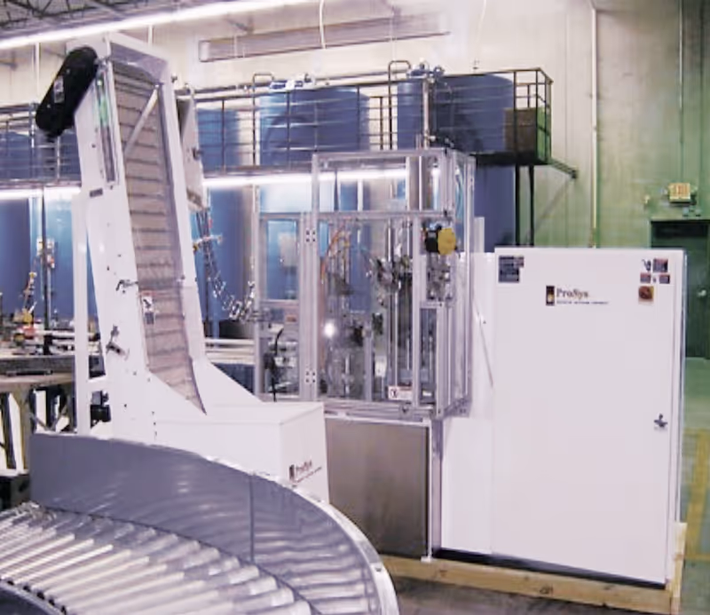 Industrial packaging machine with conveyor rollers and vertical chute in the loadmaster lubricant facility