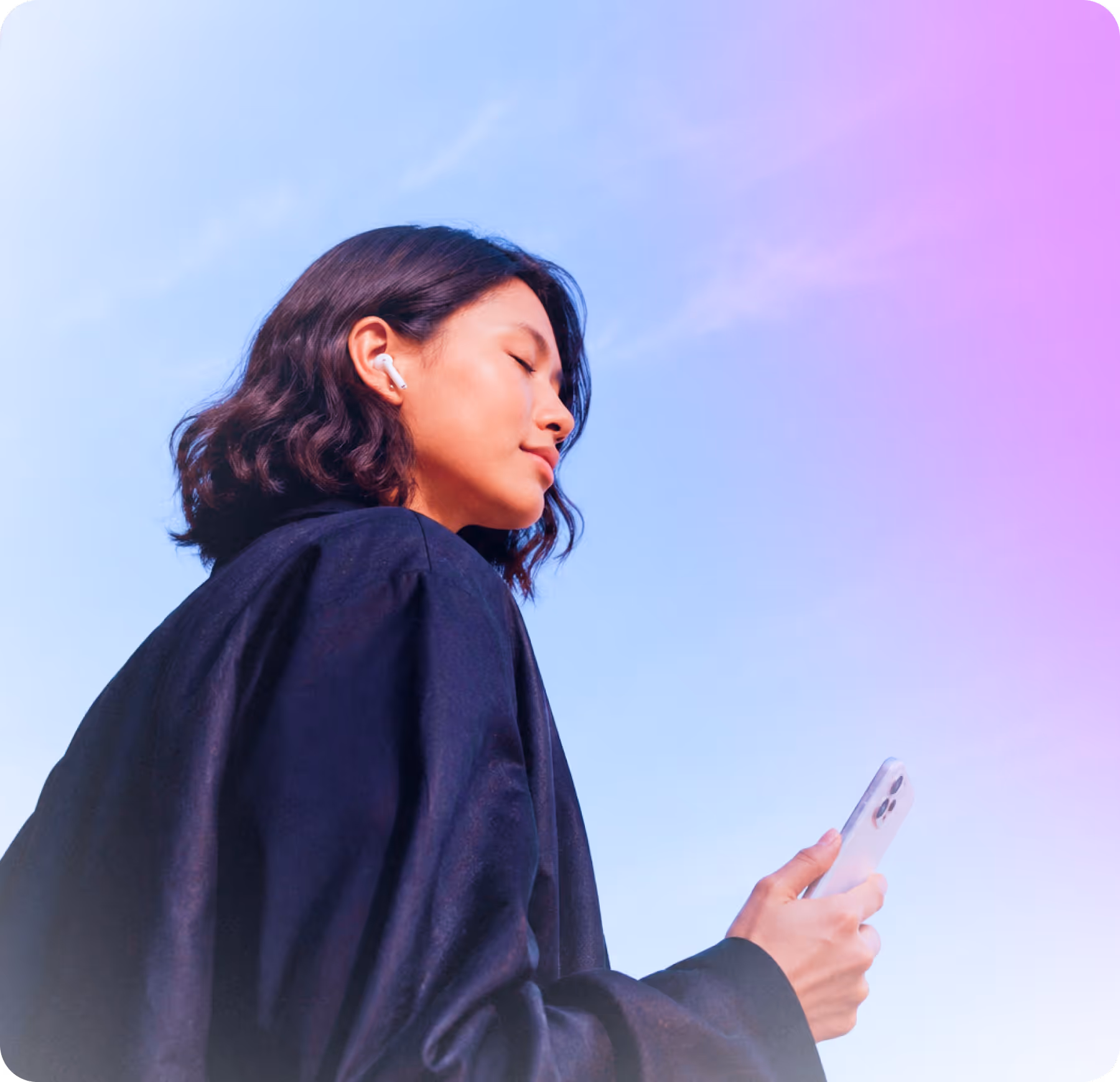 Person with earbuds holding a smartphone, eyes closed, against a blue and purple sky.