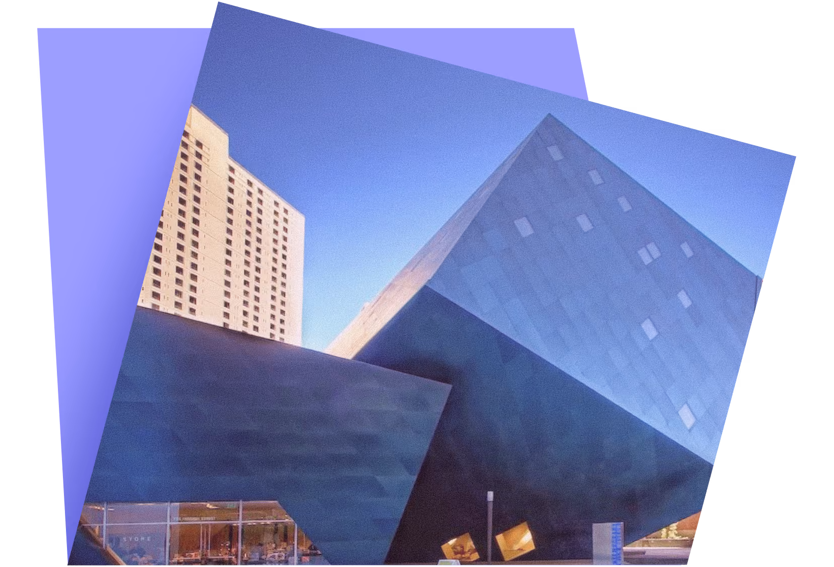 Modern angular black building with glass windows next to a tall beige apartment building under a clear sky.