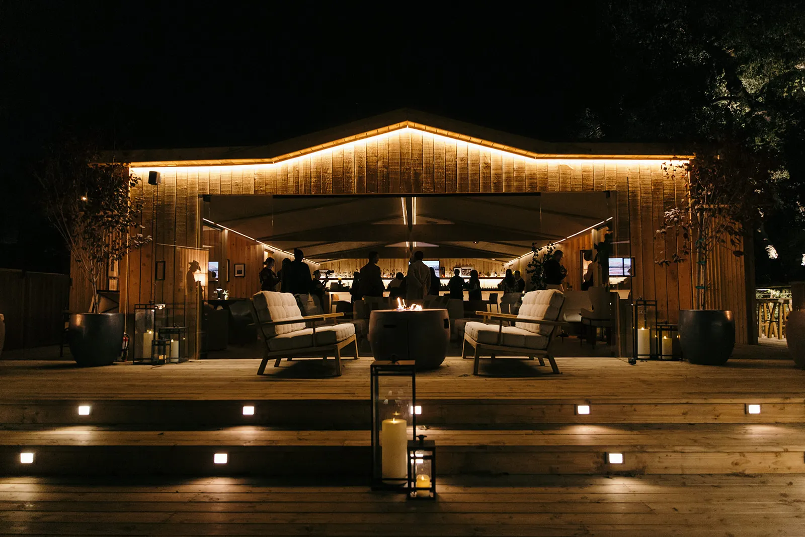 Luxury outdoor lounge at Calamigos Ranch Resort & Spa in Malibu, featuring a warmly lit pavilion, modern seating, and fire pit for evening gatherings and events.