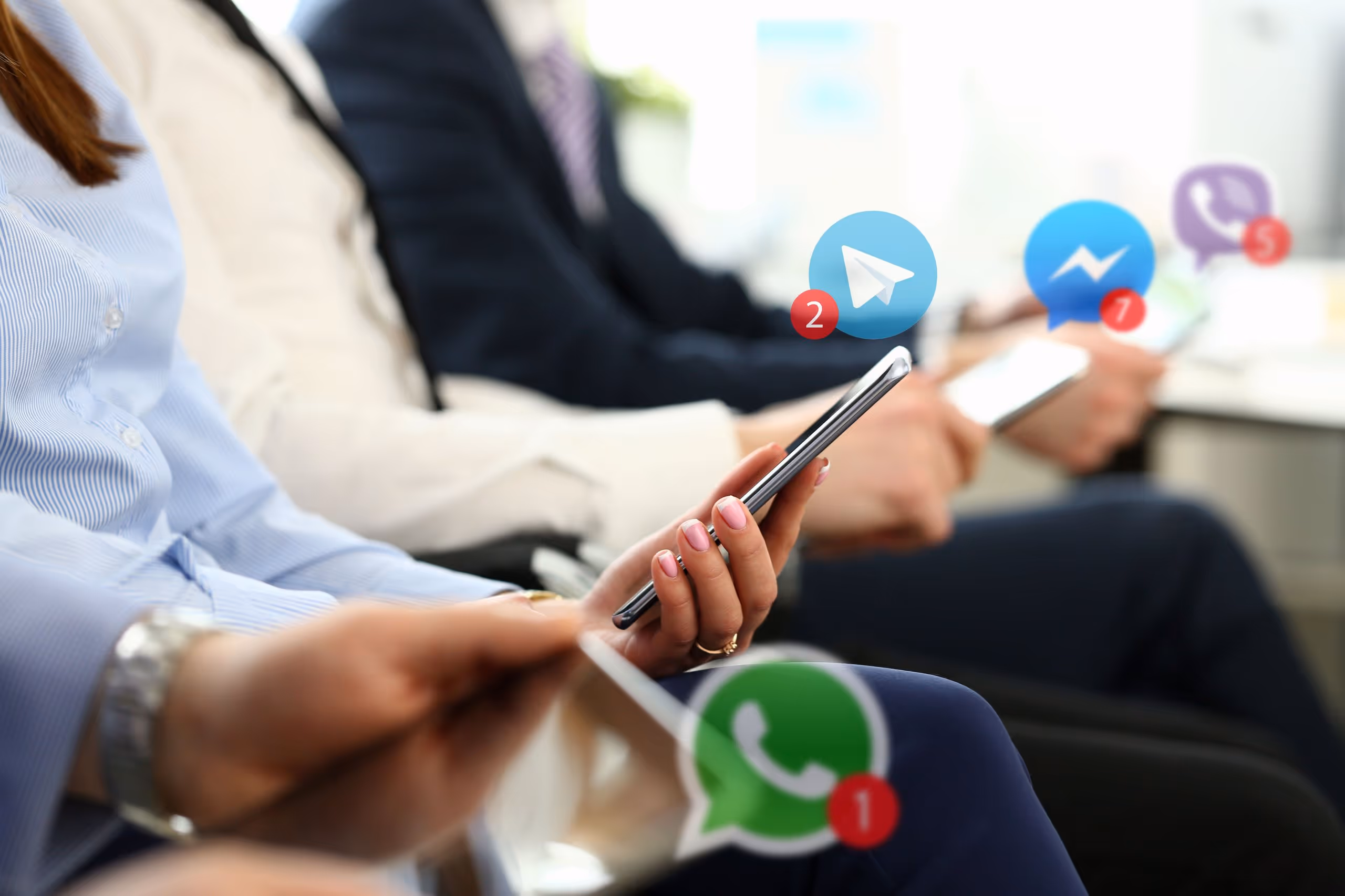 Vier Personen halten Smartphones in der Hand, auf denen Symbole von Telegram, Facebook Messenger, Viber und WhatsApp mit Benachrichtigungszählen angezeigt werden.