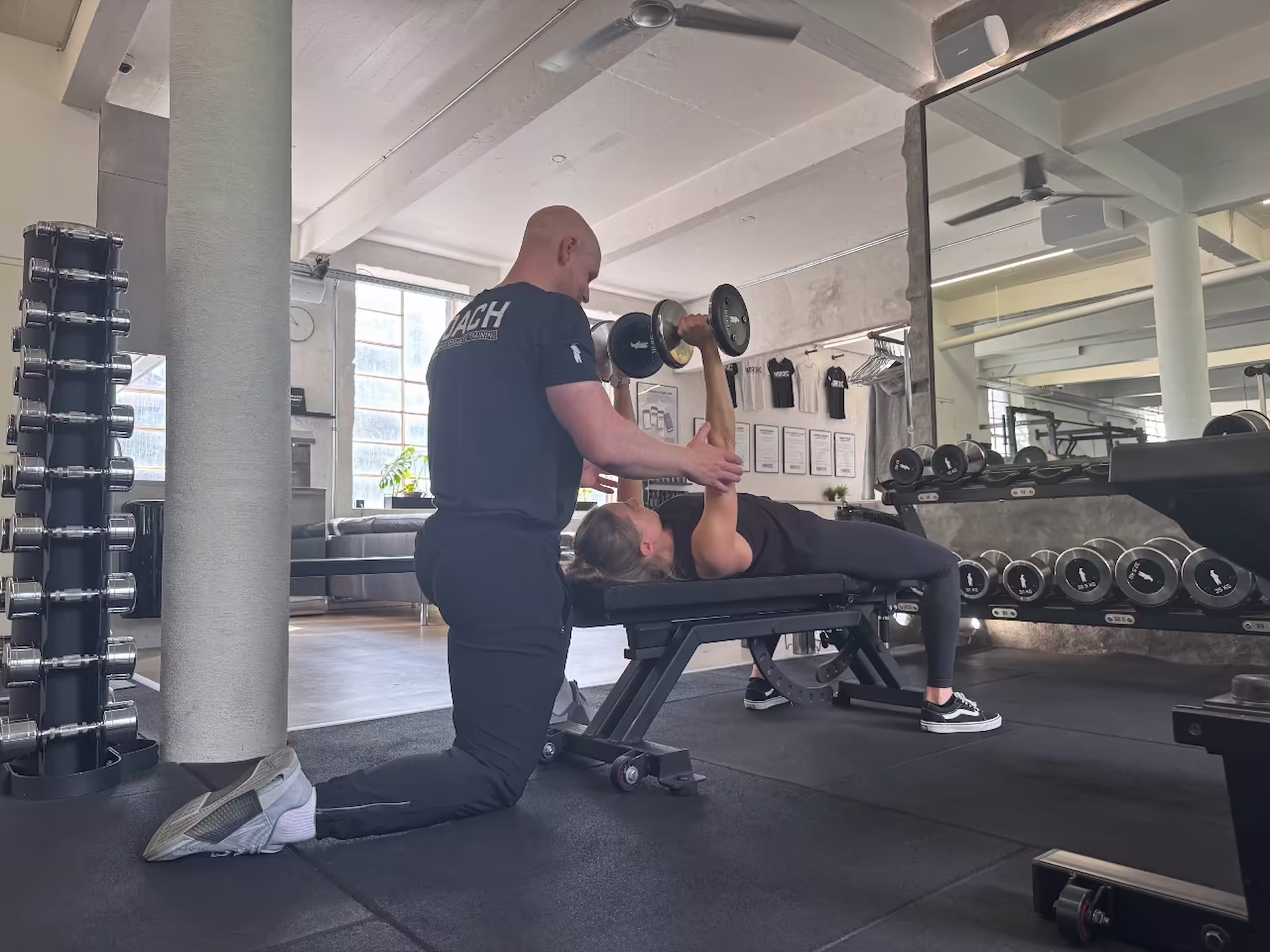 Personlig træner og fysioterapeut coacher klient i brystpres med håndvægte hos Nordic Performance Training i København – med fokus på korrekt teknik, styrke og kontrol.