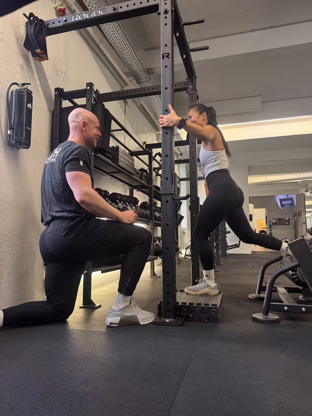 Personal trainer and physiotherapist guiding a client through a set of split squats at Nordic Performance Training’s private gym in Copenhagen, focusing on balance, technique, and controlled strength progression.