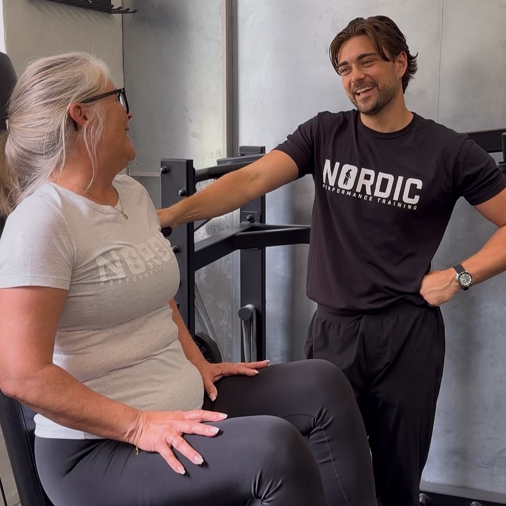 Kvindelig klient smiler og er glad fordi hendes træner nu er fast og struktureret sammen med sin personlige træner i Nordic Performance Training i København.