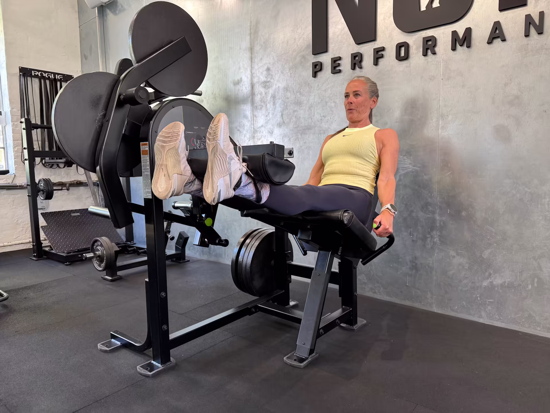 Charlotte, a 56-year-old CEO, performing leg extensions at Nordic Performance Training’s private gym in Copenhagen, showcasing strength, consistency, and structured strength training.
