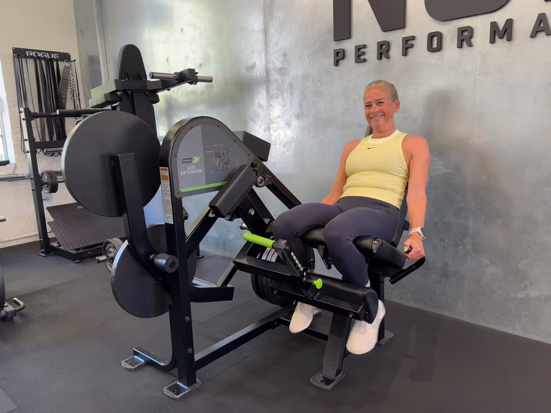 60-year-old client smiling after completing a set of leg extensions at Nordic Performance Training’s private gym in Copenhagen, highlighting strength and motivation through guided training.