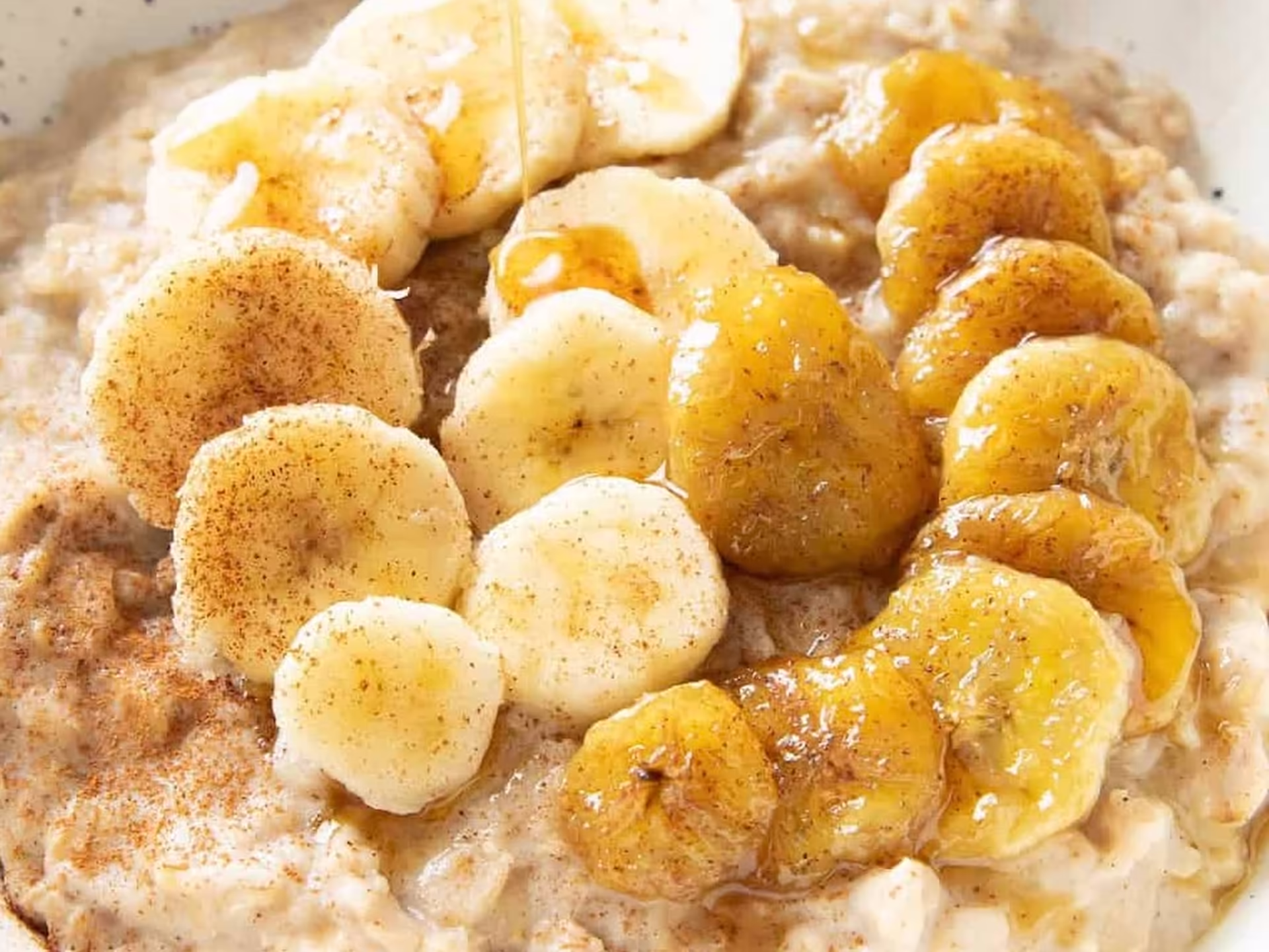 A bowl of protein-rich oatmeal topped with honey, cinnamon, and bananas, illustrating a nutritious and balanced breakfast for strength training and recovery.