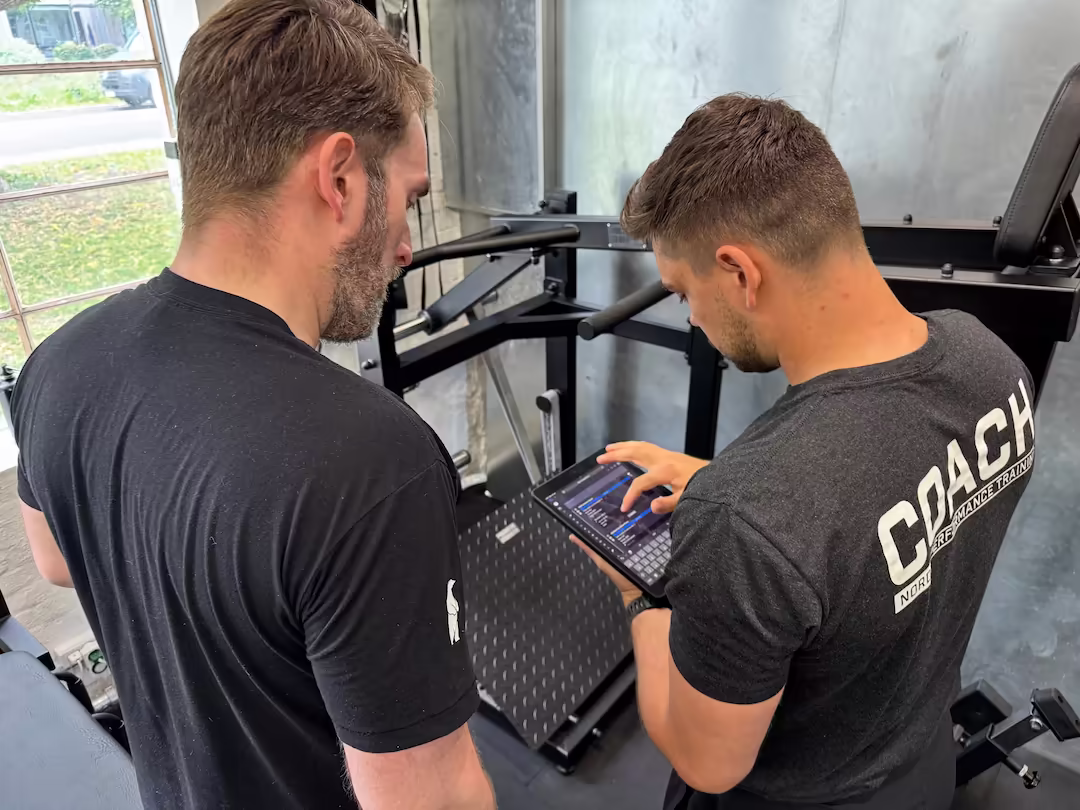 Coach and physiotherapist at Nordic Performance Training reviewing a client’s program on a tablet, demonstrating the philosophy of structured, simple, and trackable full body training.