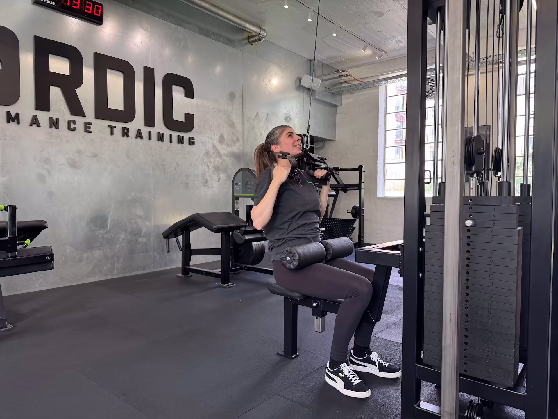 Rose, a 35-year-old digital merchandiser, performing a cable pulldown at Nordic Performance Training’s private gym in Copenhagen, demonstrating focus, strength, and structured training.
