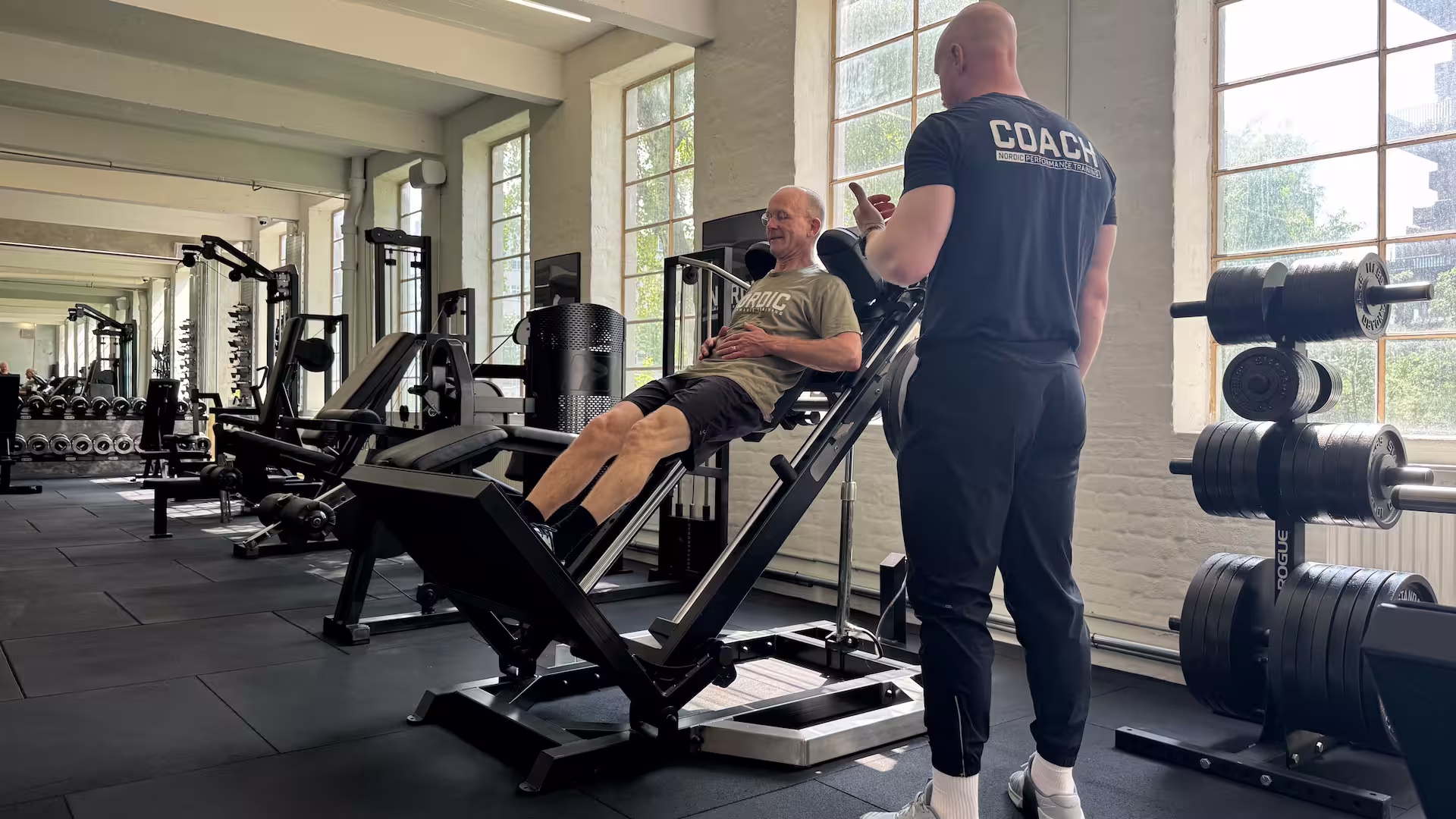 Klient er glad og laver hack squat under en personlig træningstime  i Nordic Performance Trainings private træningscenter i København.