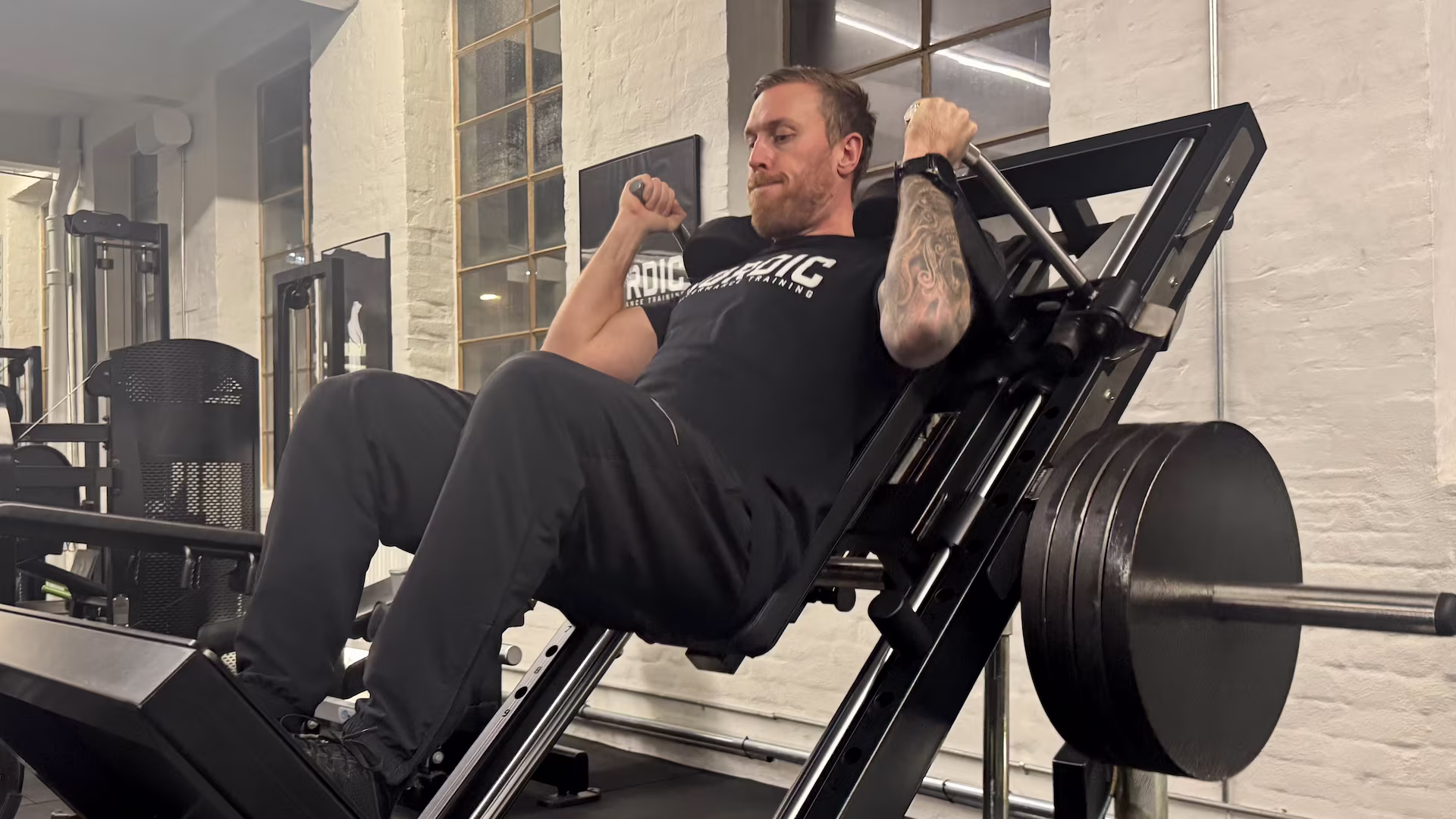 Anders udfører tunge hack squats hos Nordic Performance Training uden smerter.