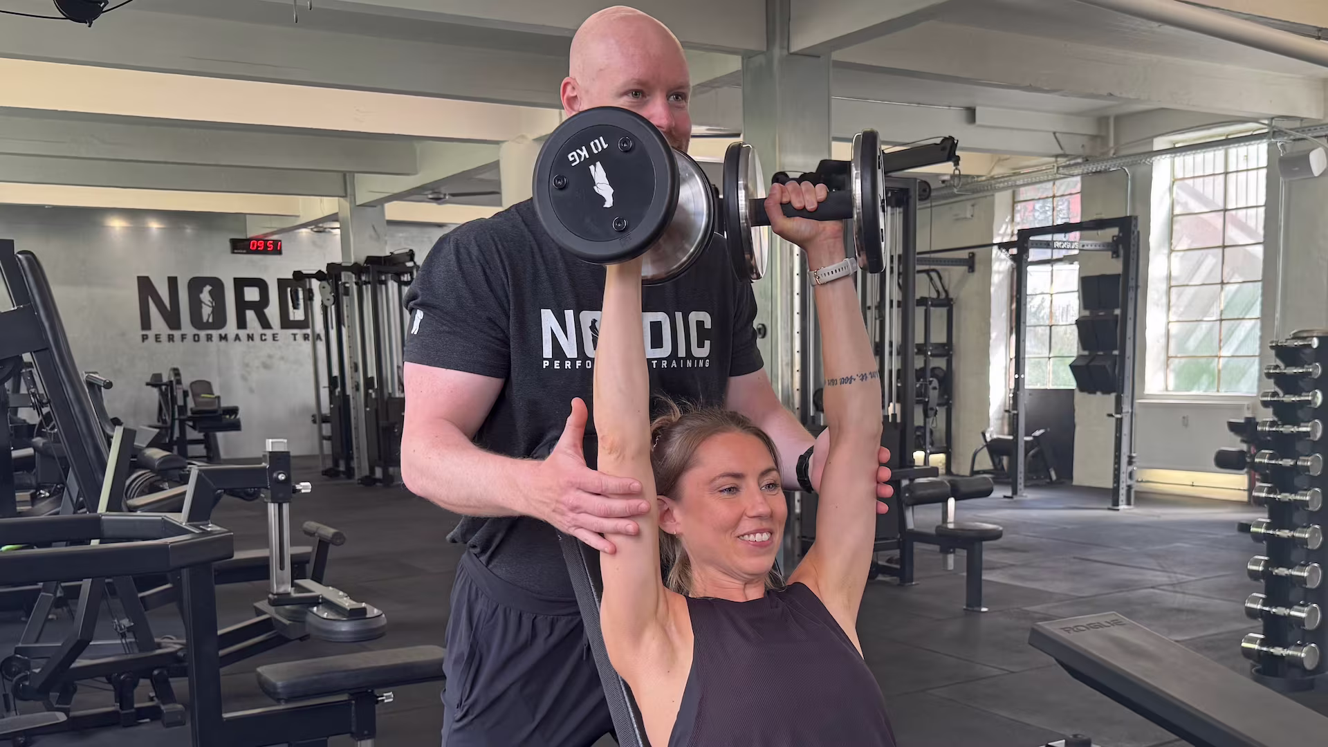 Klient udfører skulderpres sammen med sin personlig træner i Nordic Performance Training i København..