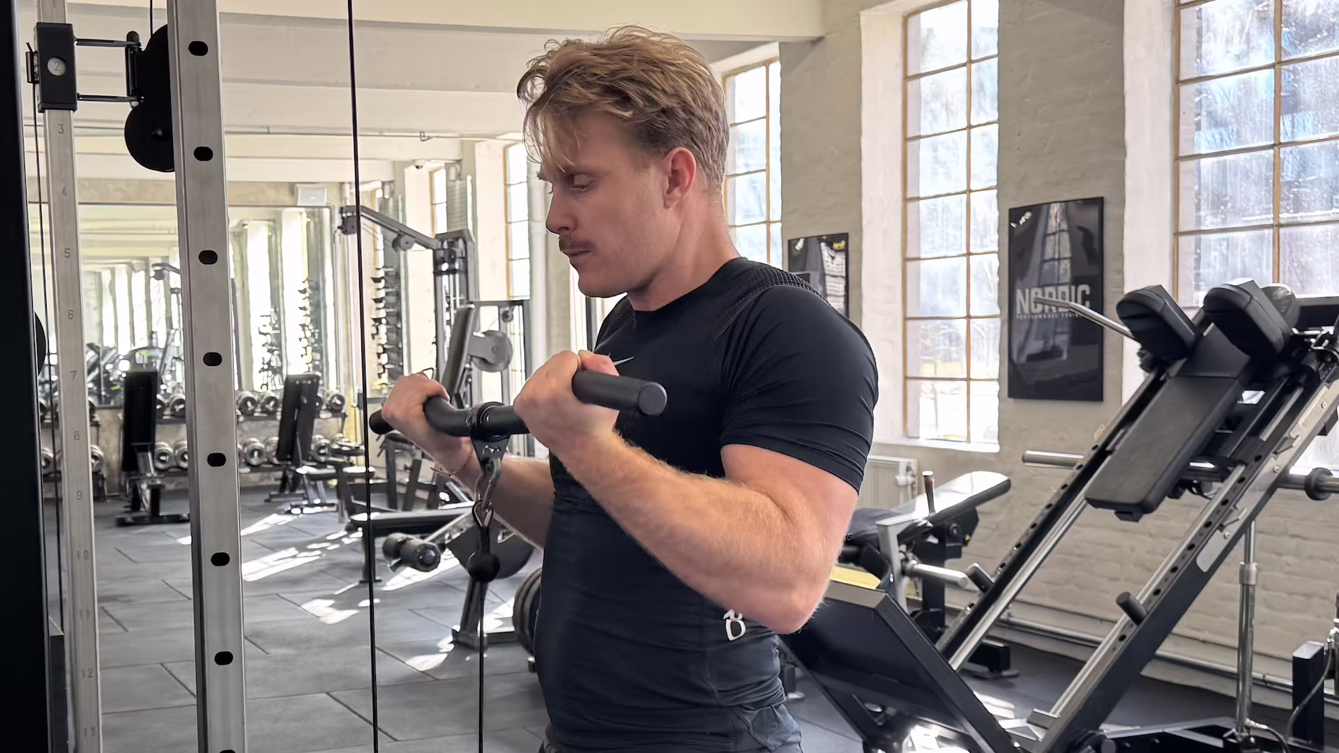 Klient udfører EZ-bar cable curl hos Nordic Performance Training under sin personlige træningssession.