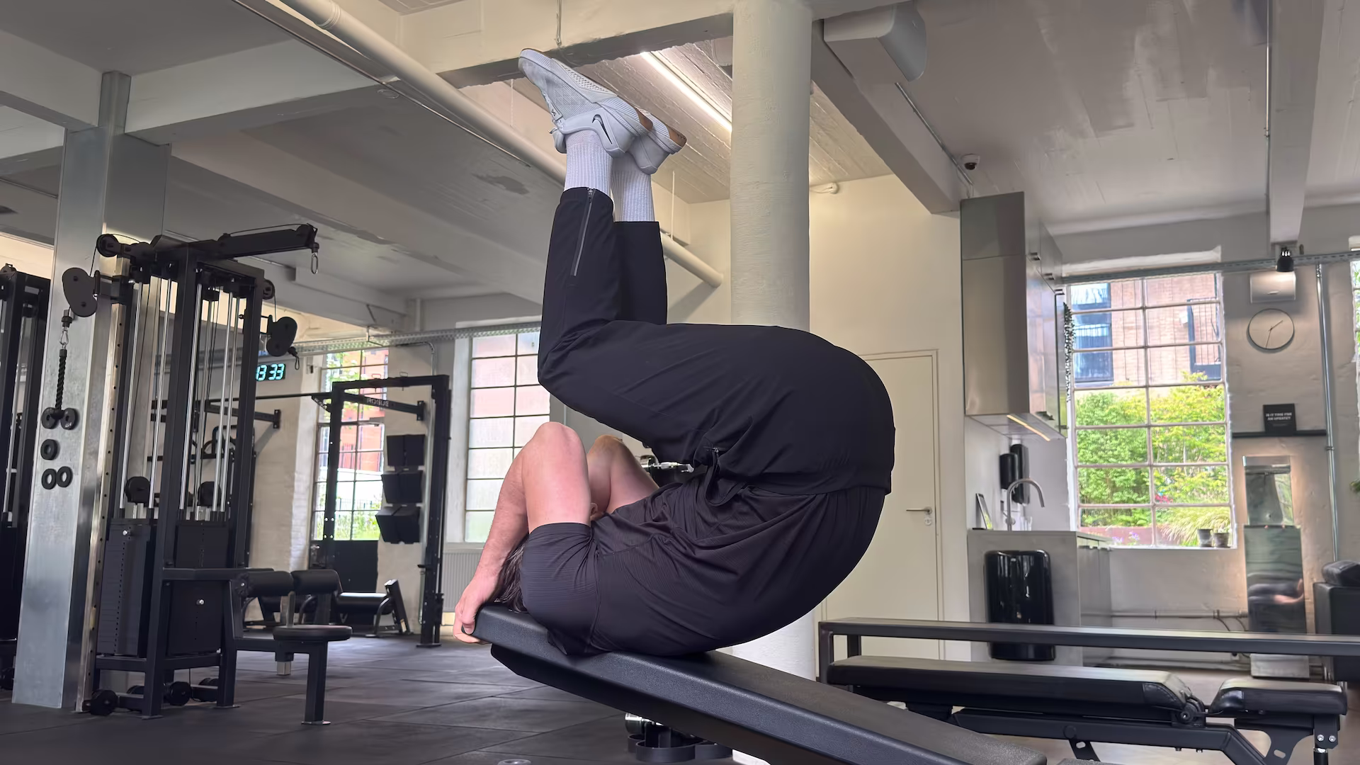 Personlig træner og fysioterapeut Simon demonstrerer Reverse Ab Crunch på træningsbænk i Nordic Performance Training.