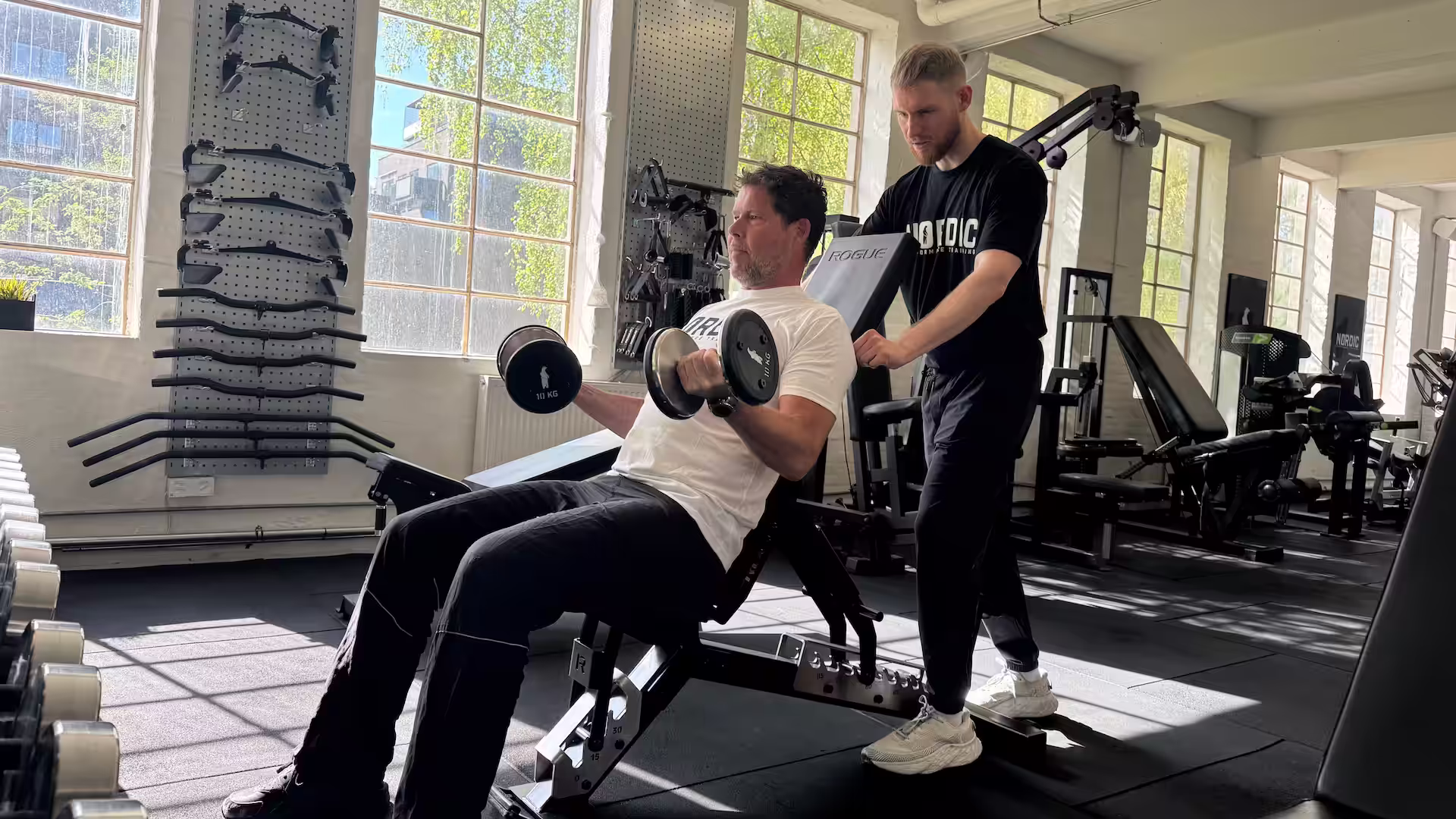 Klient udfører biceps curls under hans genoptræning af tennisalbue hos Nordic Performance Training i København.