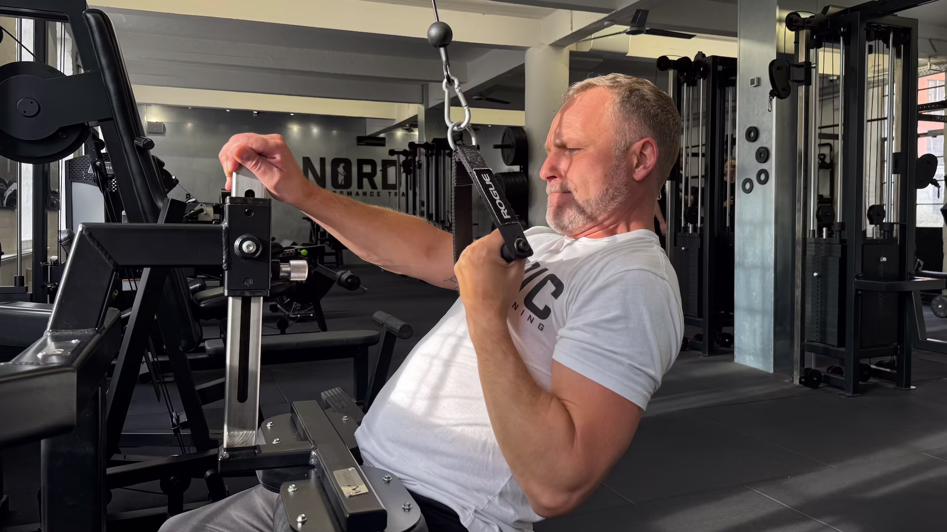 Riad udfører Single Arm Cable Pulldowns let tilbagelænet under hans genoptræning af hans ryg og skulder hos Nordic Performance Trianing i København.