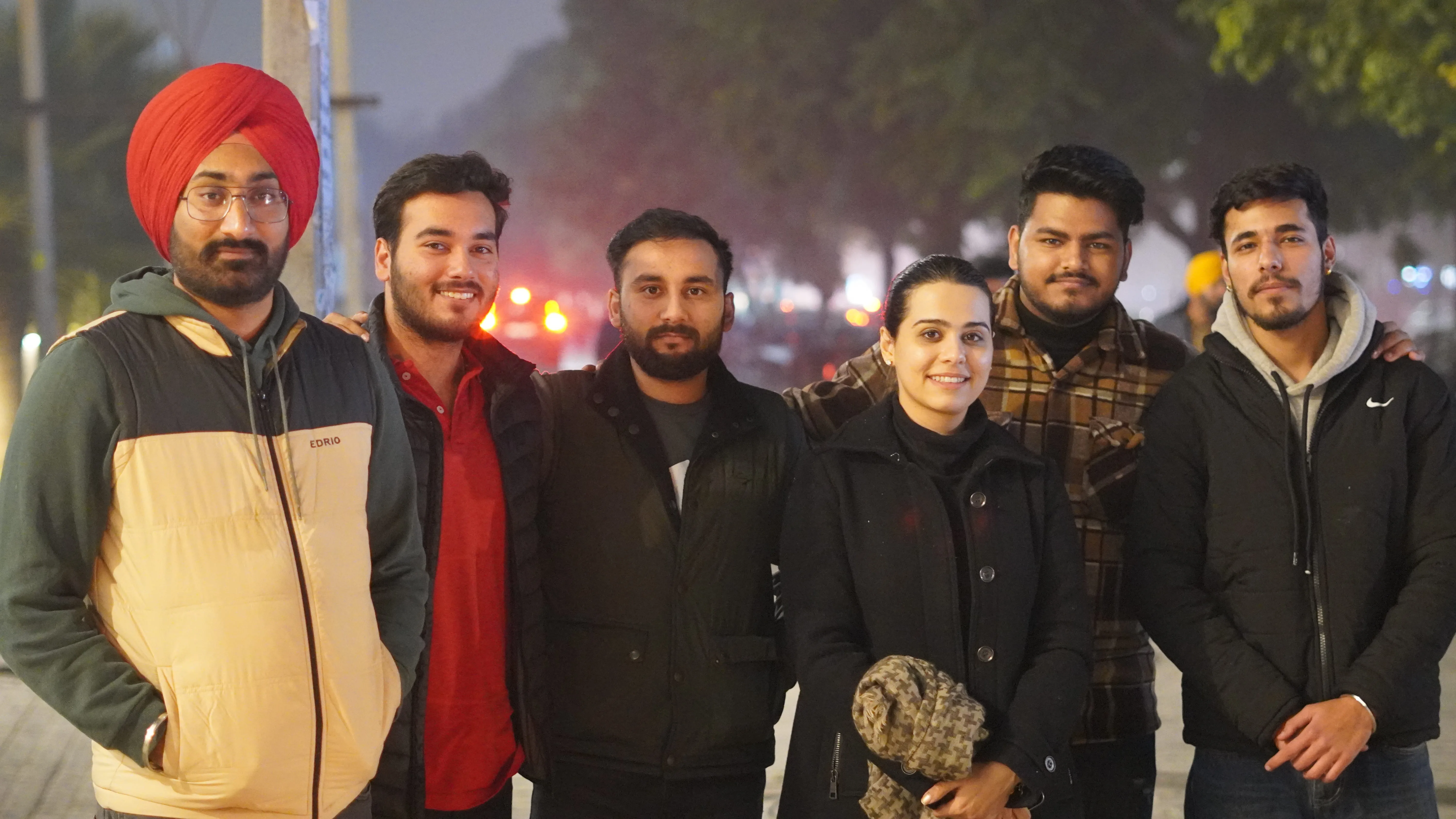 Team members enjoying an evening outing, posing together in warm winter attire with a lively, tree-lined street in the background.