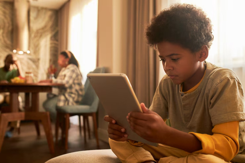 Medium shot of a young child holding a tablet, highlighting modern screen time habits, digital learning, and children's interaction with technology.