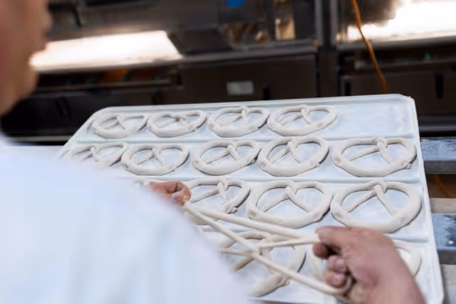 Brezel wird geknotet und zu anderen auf das Blech gelegt