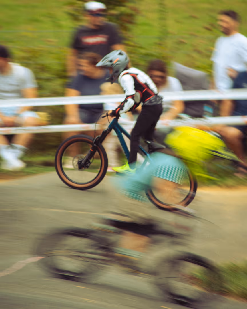 Junger Teilnehmer beim Mountainbike-Rennen auf dem Pumptrack, Zuschauer verfolgen das Rennen
