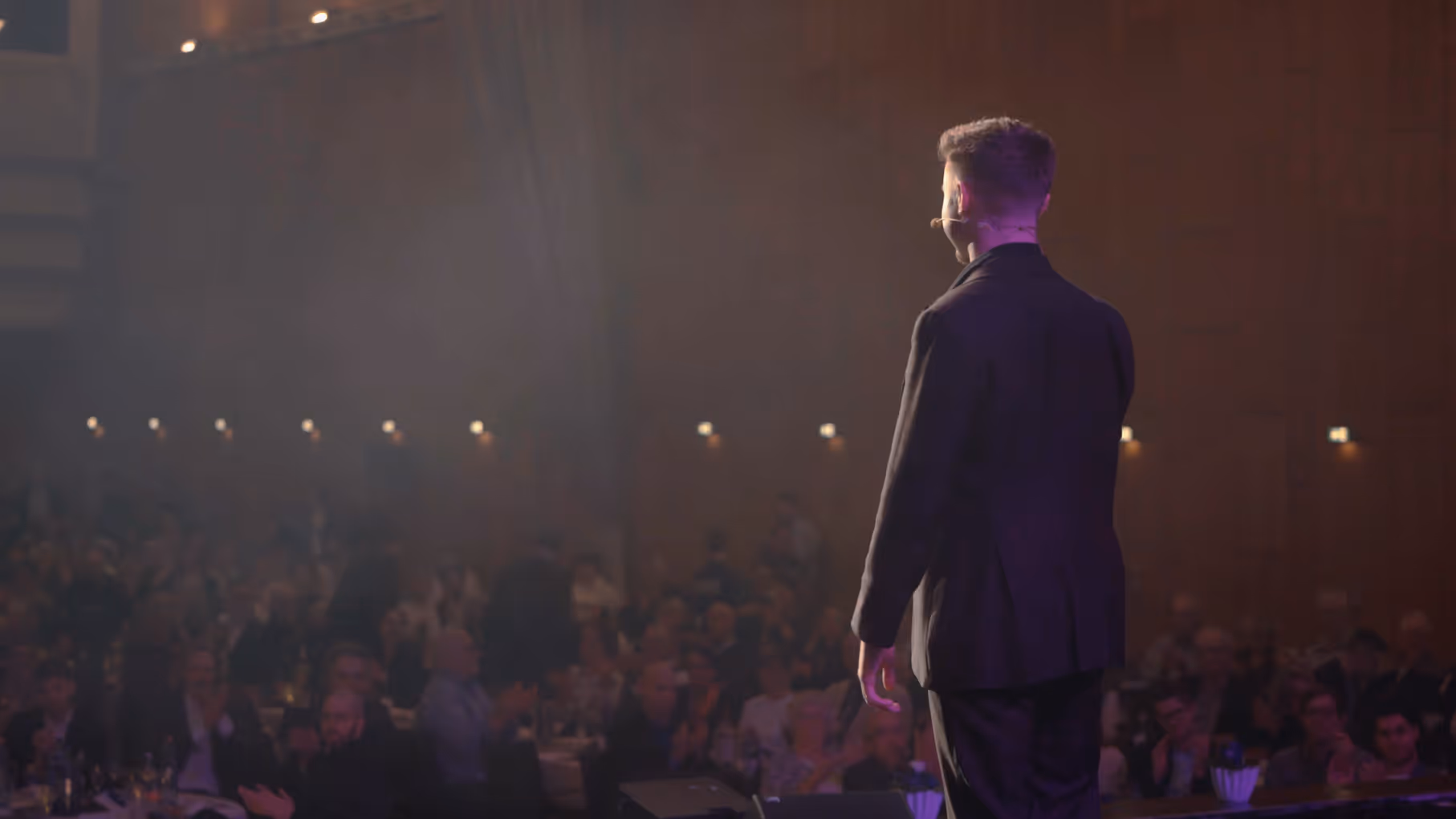 Rückenansicht von Zauberer Michael Peskov auf der Bühne vor riesigem Publikum – Cinematisches Website Hero-Video zur Inszenierung der Show-Größe.